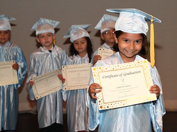 Pre-K students dressed in their graduation cap and gown holding diplomas