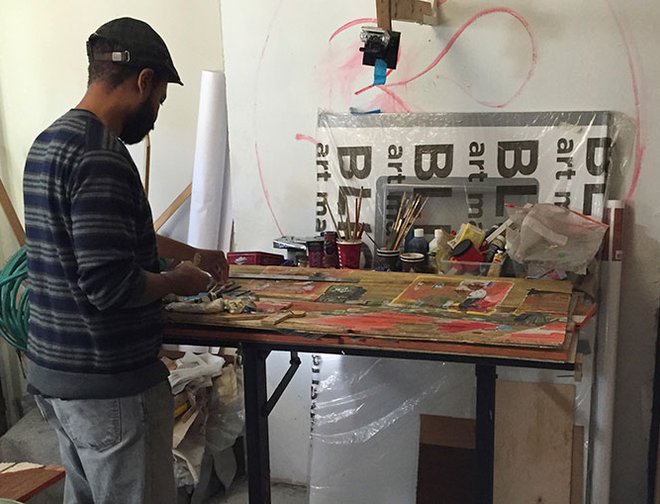 Artist Javaka Steptoe creating artwork at his worktable. 