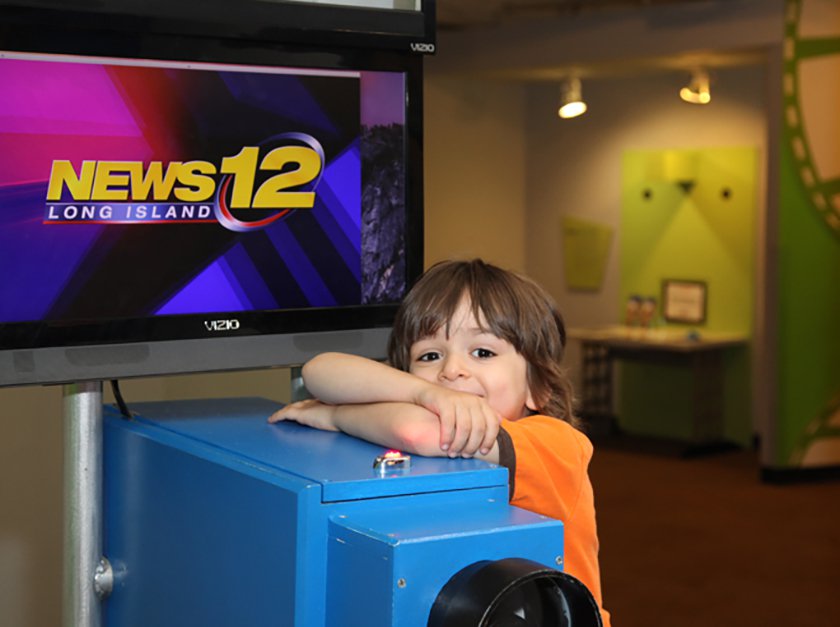 A child leaning on the News12 wooden Camera. 