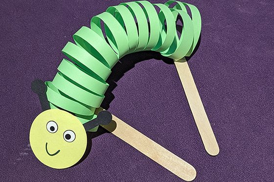 A spiraled green and yellow paper caterpillar puppet. 