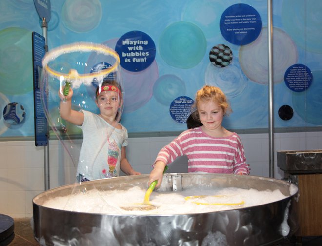 Two girls using bubbles wands to make bubbles. 
