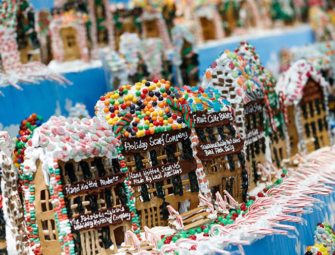 Rows of gingerbread houses decorated with white frosting and a variety of candy. 