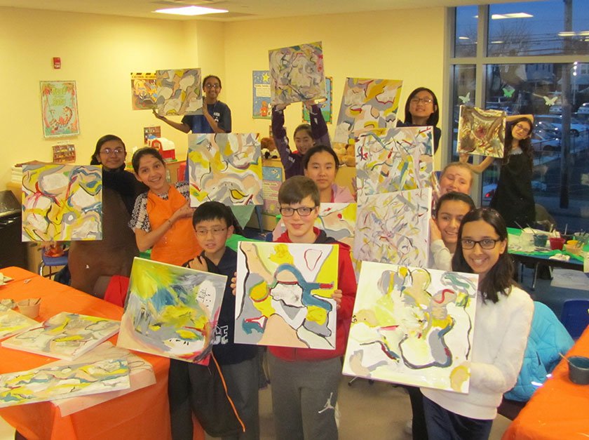 A group of adolescents holding up their DeKooning artwork in a classroom. 