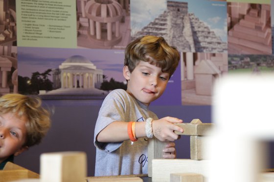 A boy creating a structure using wooden blocks. 