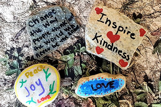 Four rocks painted with symbols and positive messages.