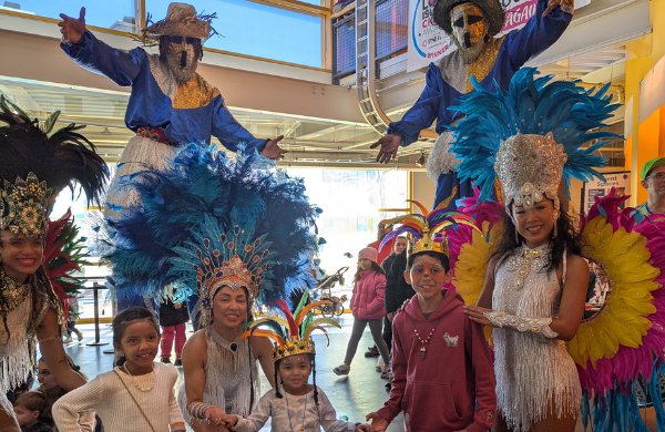 A group of children, two stilt walkers, and dancers. 