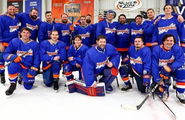 Eighteen hockey players lined up in two rows wearing blue LI Warriors uniforms.