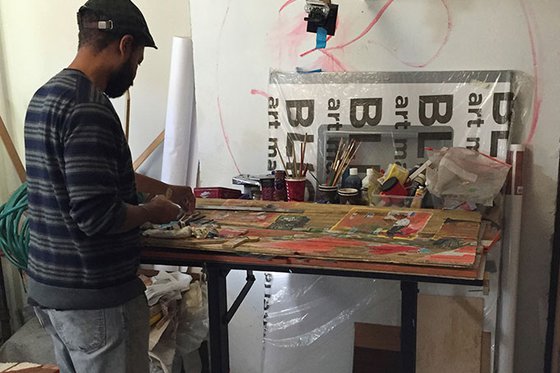 Artist Javaka Steptoe creating artwork at his worktable. 