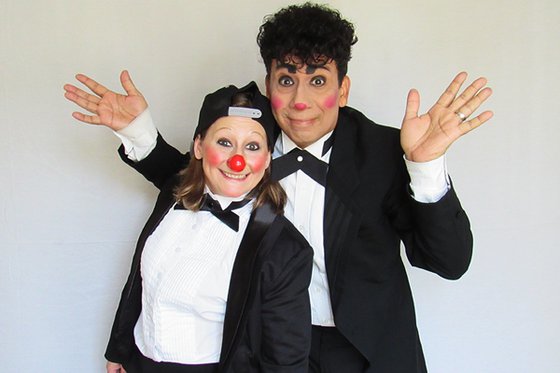 A man and woman dressed in a black suit with a red nose and red cheeks. 