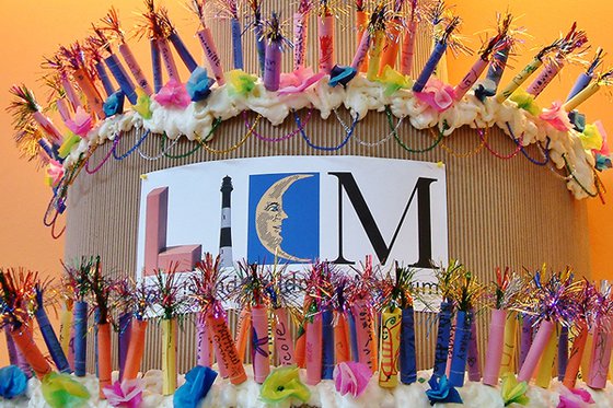 Giant cardboard birthday cake with paper candles and LICM logo. 