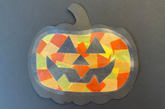 Paper jack-o-lantern collage made with orange and yellow pieces of paper.