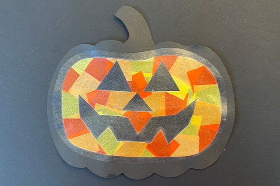 Paper jack-o-lantern collage made with orange and yellow pieces of paper.