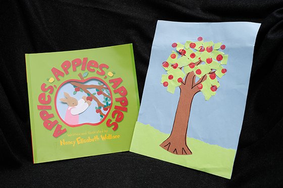 The book Apples, Apples Apples, next to a painted picture of an apple tree. 