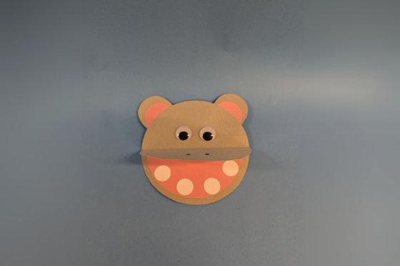 A grey circular hippo face, a large open mouth and goggly eyes. 