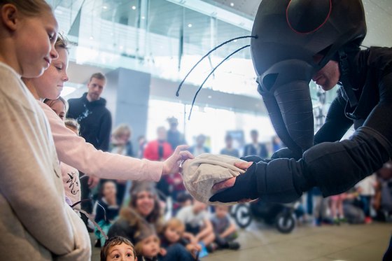 A person in a large ant costume interacting with children. 