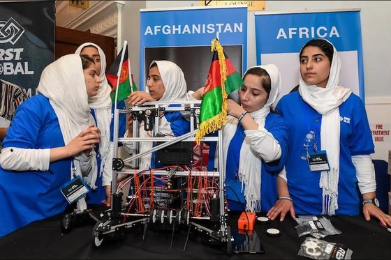 Five adolescent girls wearing blue t-shirts and headscaves as a part of the Afghan Girls Robotics Team. 