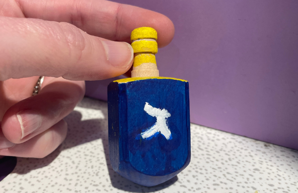 Blue dreidel inscribed with white Hebrew letter gimel.