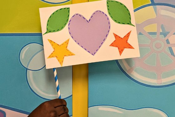 A paper small flag decorated with color stars, a heart and leaves. 