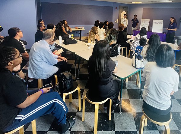 A group of adults sitting at tables all watching as a speaker presents. 