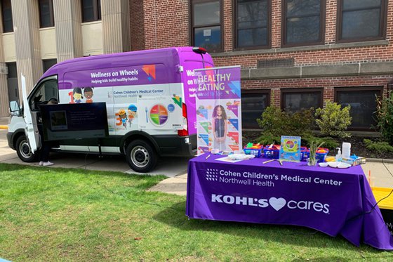 A purple and white fan in the background of a table with a table cloth that reads " Cohens Children's Medical Center, Northwell Health" and "Kohls Care" 