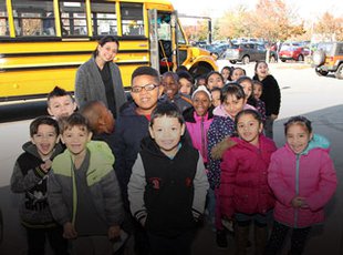 A class and their teacher waiting outside the museum in from of their school bus.
