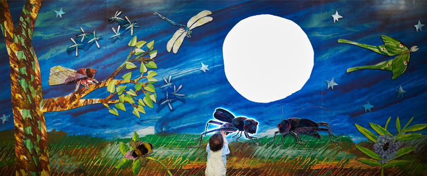 A large painted mural of a starey landscape in Eric Carle style featuring a tree, dragon flies, cicada, moths, and crickets. 