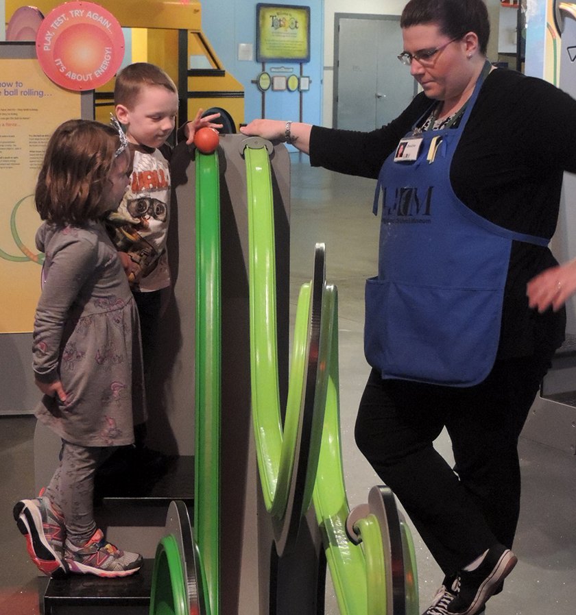A Museum Educator helping two visitors create their rollercoaster arcs. 