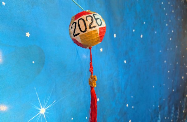 Red, white, and gold paper lantern with "2026" written in black, with a red tassel and gold horse charm attached.