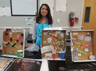 LICM staff member standing next to three mazes made from straws, paper, tape and cups by students. 