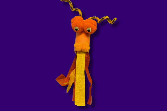 A yellow and orange dragon head made from tissue paper, pom poms and googly eyes. 