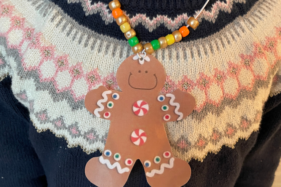 A beaded necklace with a paper gingerbread person decorated with candy stickers.
