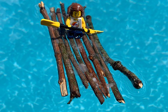 Eight sticks glued together to float in water with a lego person on top. 