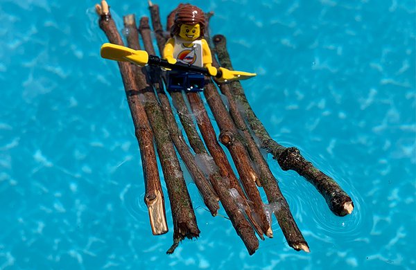 Eight sticks glued together to float in water with a lego person on top. 