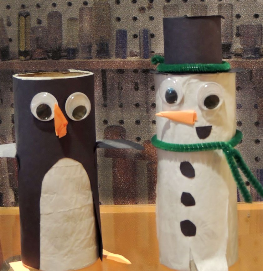 Two toilet paper rolls made into a snowman and penguin using construction paper. 