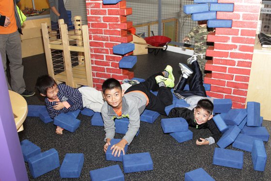 Boys laying on the floor after knocking over their brick wall creation. 