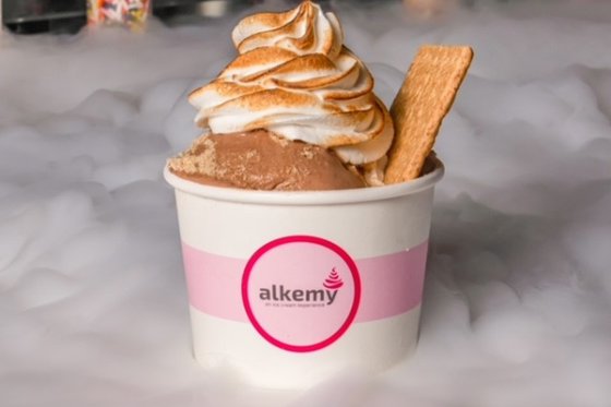 Ice cream in a cup with toasted marshmallow fluff on top surrounded by dry ice vapor.