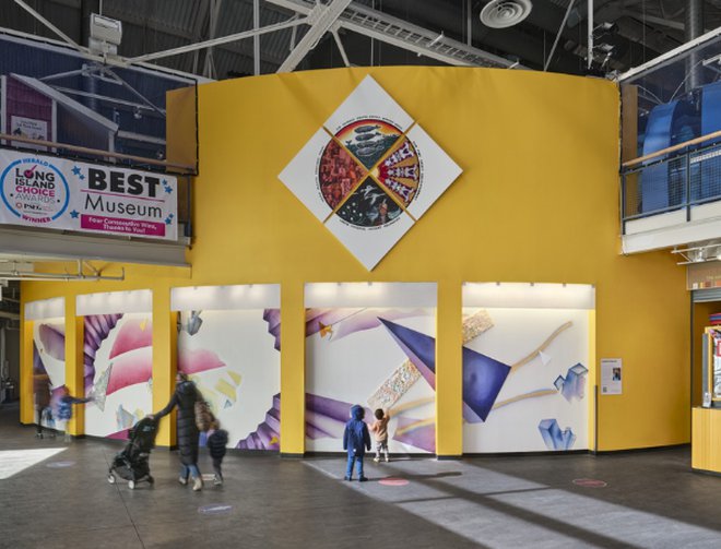Wide view of the LICM Outer Lobby showing geometric art on white bay walls. Photo by Garrott Carroll