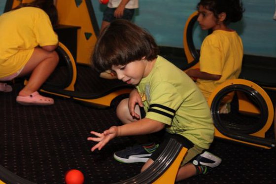 A child sitting placing a ball on a a track. 
