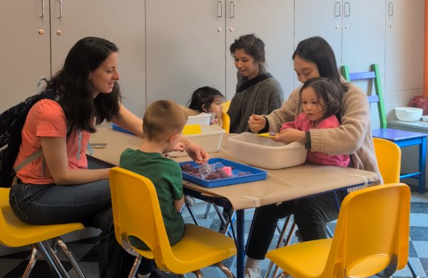 A group of children and adults sitting together at a table doing sensory play. 
