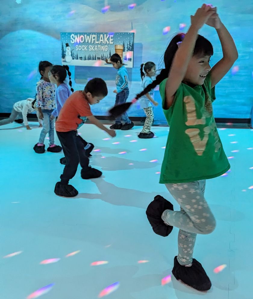 A group of children 'skating' while wearing booties over their shoes. 