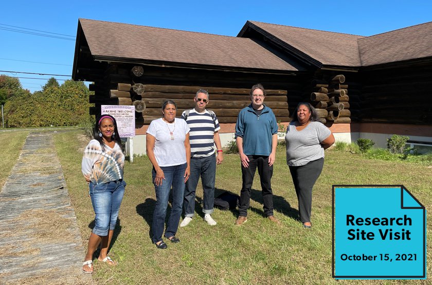 A group of five people, two LICM exhibits staff members, and three consultants standing in front of a log cabin.