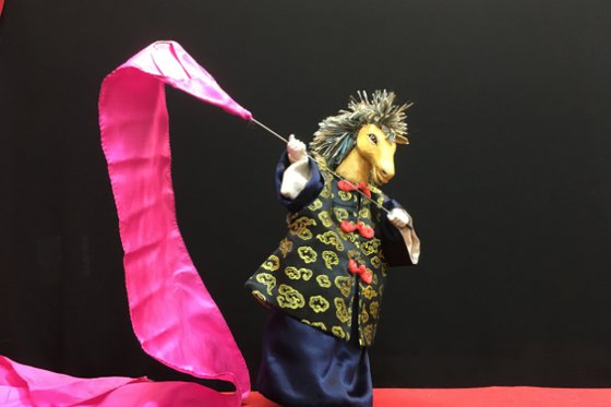 Chinese horse puppet with pink banner on black background. 