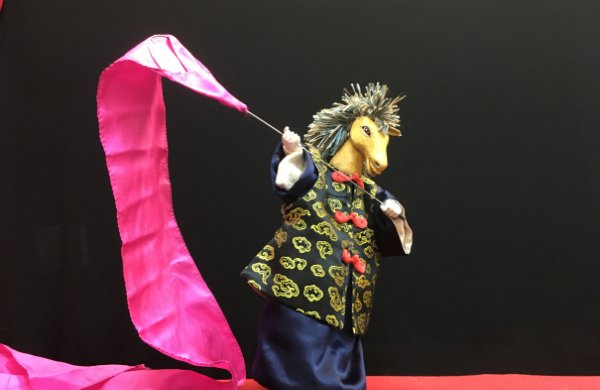 Chinese horse puppet with pink banner on black background. 