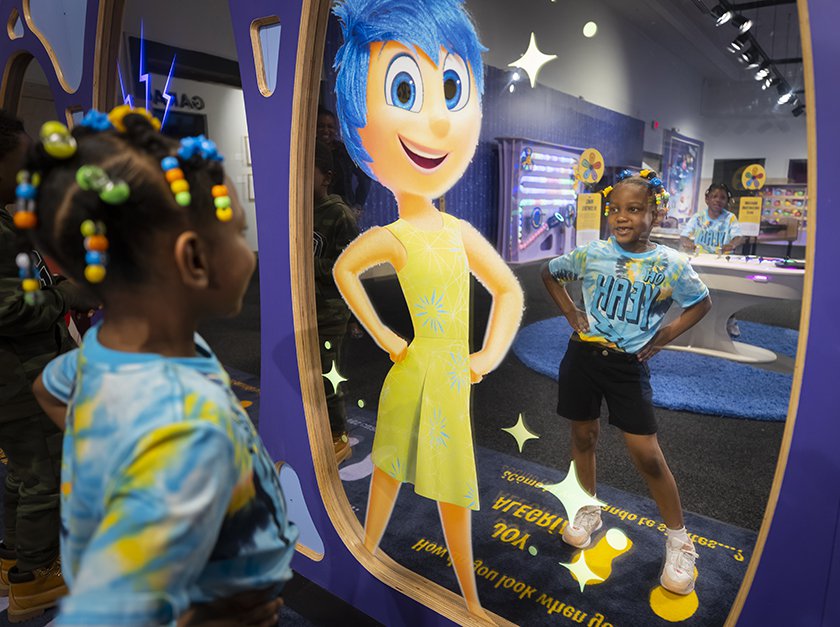 A large mirror with a graphic of character Joy and a child looking into the mirror with her hands on her hips. 