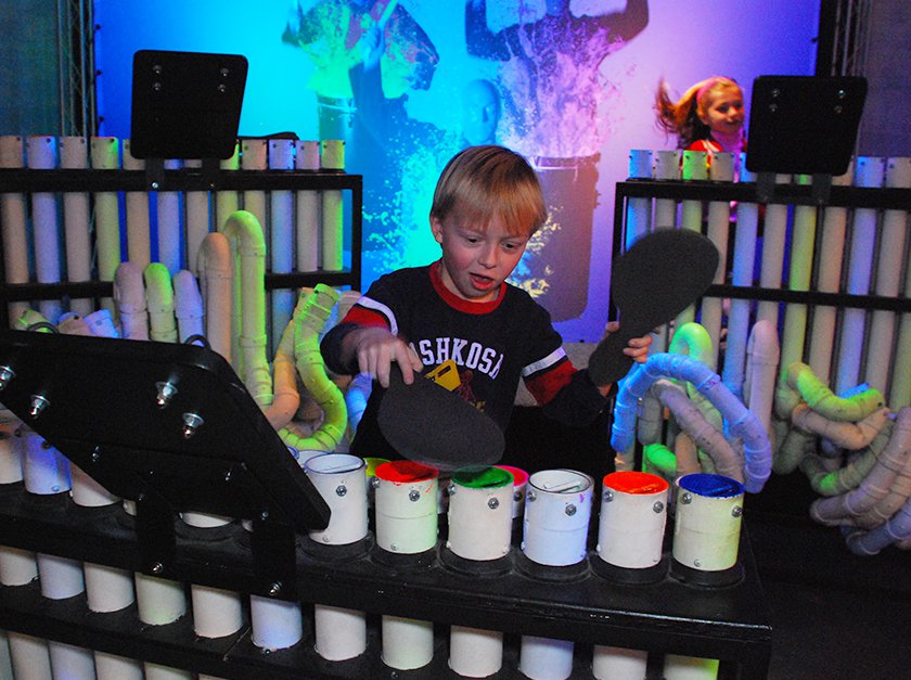 A young visitor creating music with different colored painted tubes. 