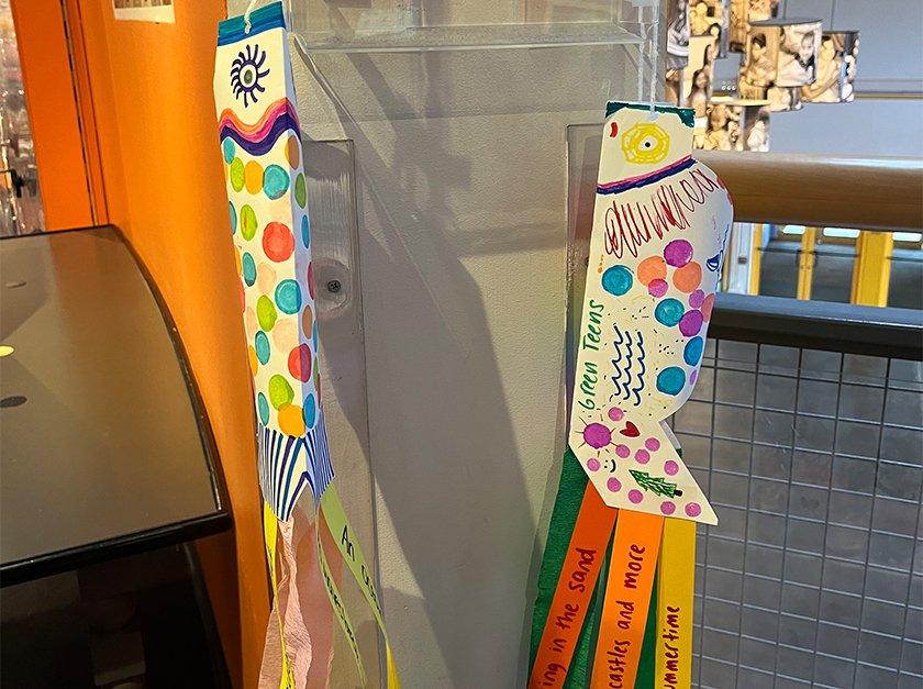 Two colorful carpe shaped windsocks hanging in an LICM exhibit. 