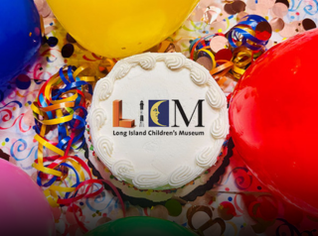 A white cake with the LICM logo on it surrounded by balloons. 