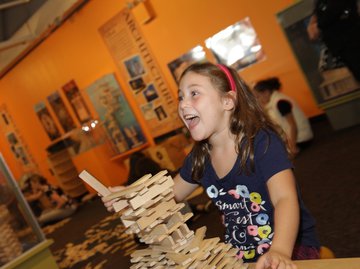 A girl playing with KEVA blanks and building a structure.