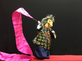 Chinese horse puppet with pink banner on black background