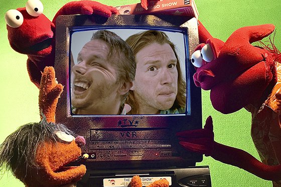 Photo of a TV being looked at by three puppets. Inside the TV, two people are pushing up against the screen.